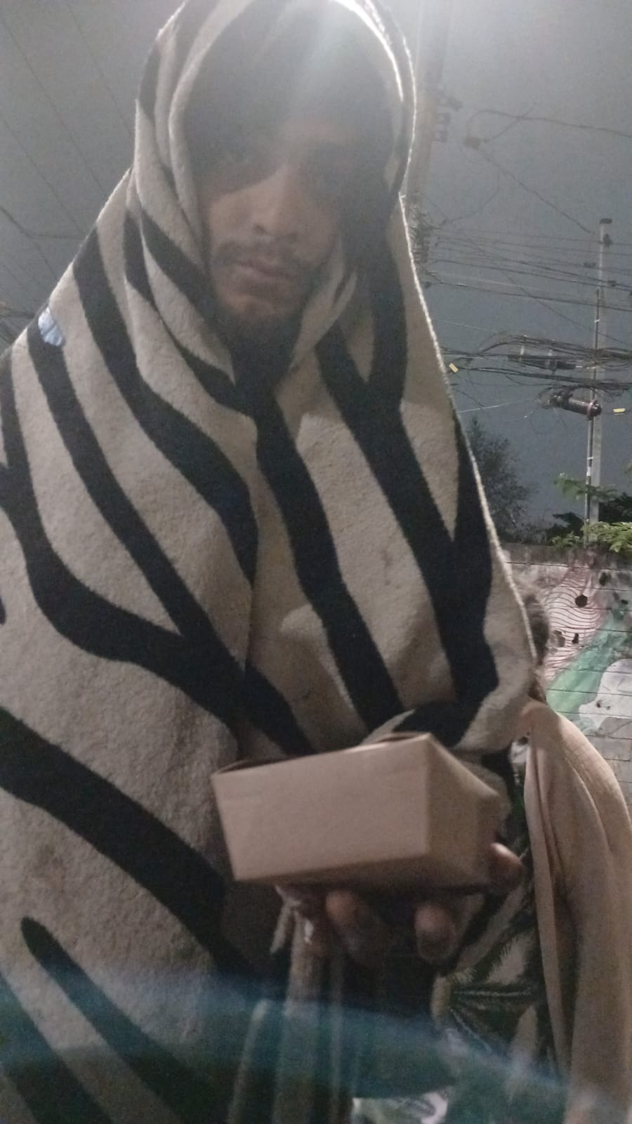 Beneficiário segurando uma refeição durante uma entrega noturna