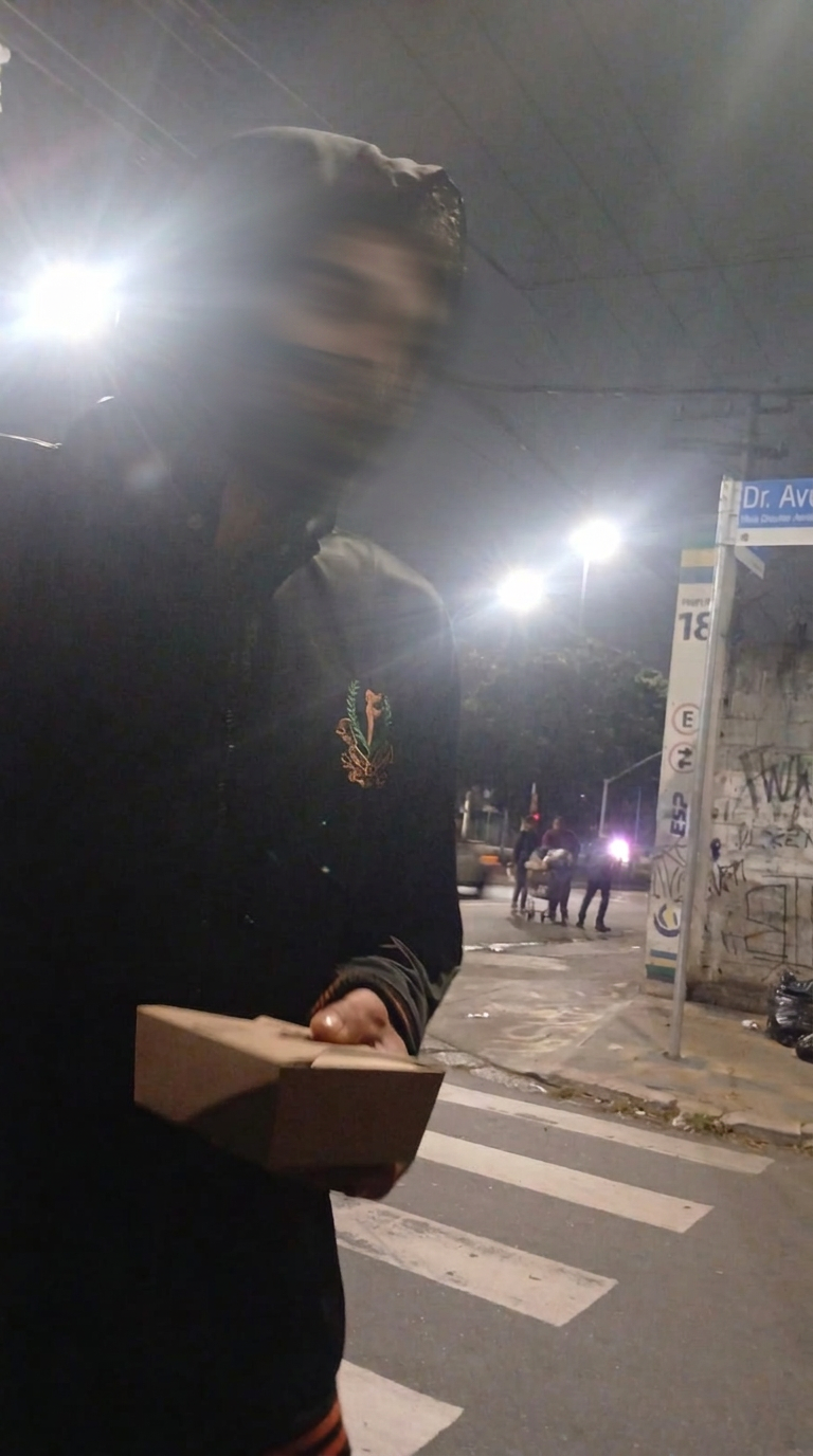 Pessoa recebendo uma refeição durante uma entrega noturna