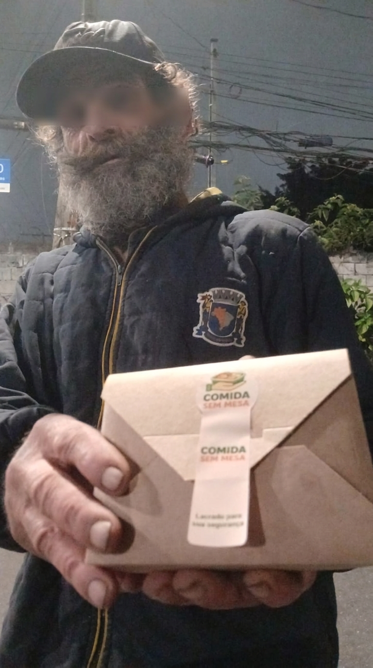 Beneficiário mostrando uma embalagem do Comida Sem Mesa